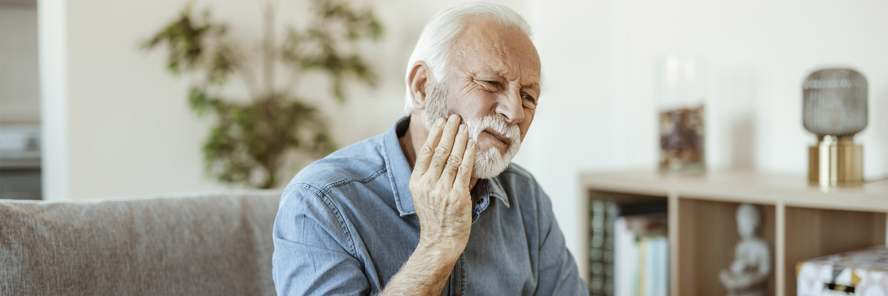 Elderly man with toothache emergency prepping to call his dentist in Idaho Falls, Dr. Michael Elison.