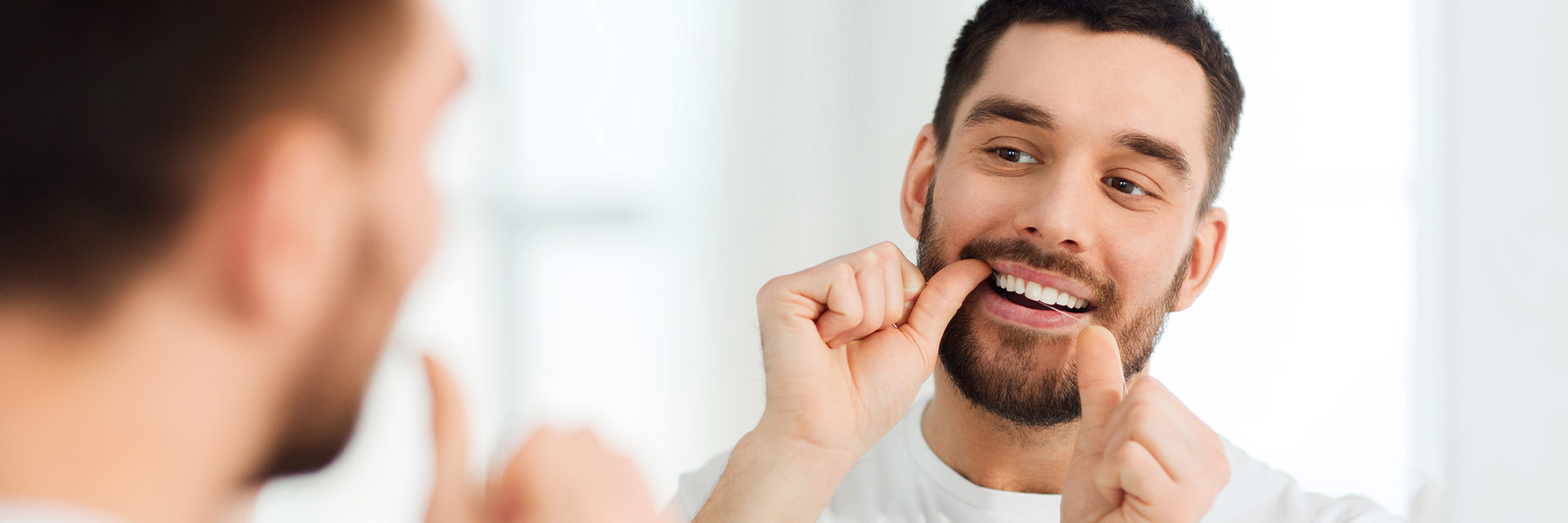 Man flossing teeth after visiting his family dentist in Idaho Falls, Dr. Michael Elison.