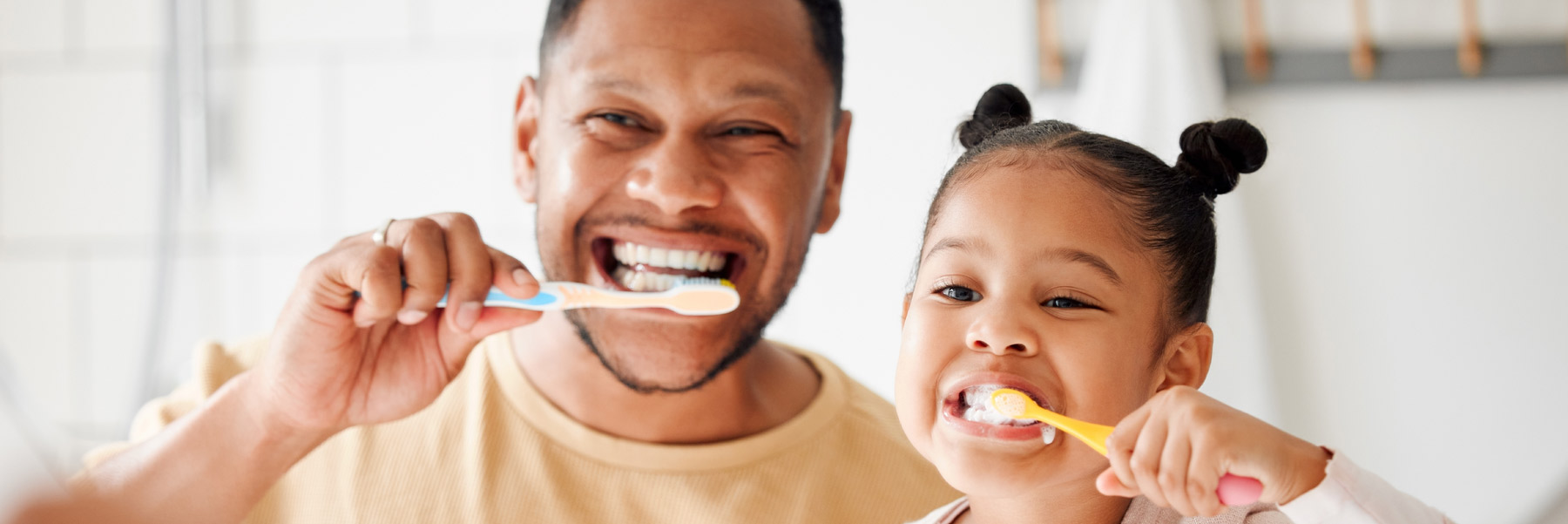 Father and daughter, brushing teeth after visiting their family dentist in Idaho Falls, Dr. Michael Elison.